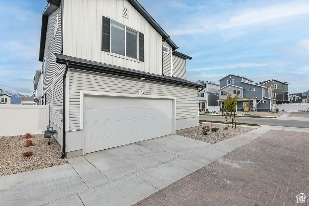 View of side of property featuring a garage, fence, a residential view, and concrete driveway
