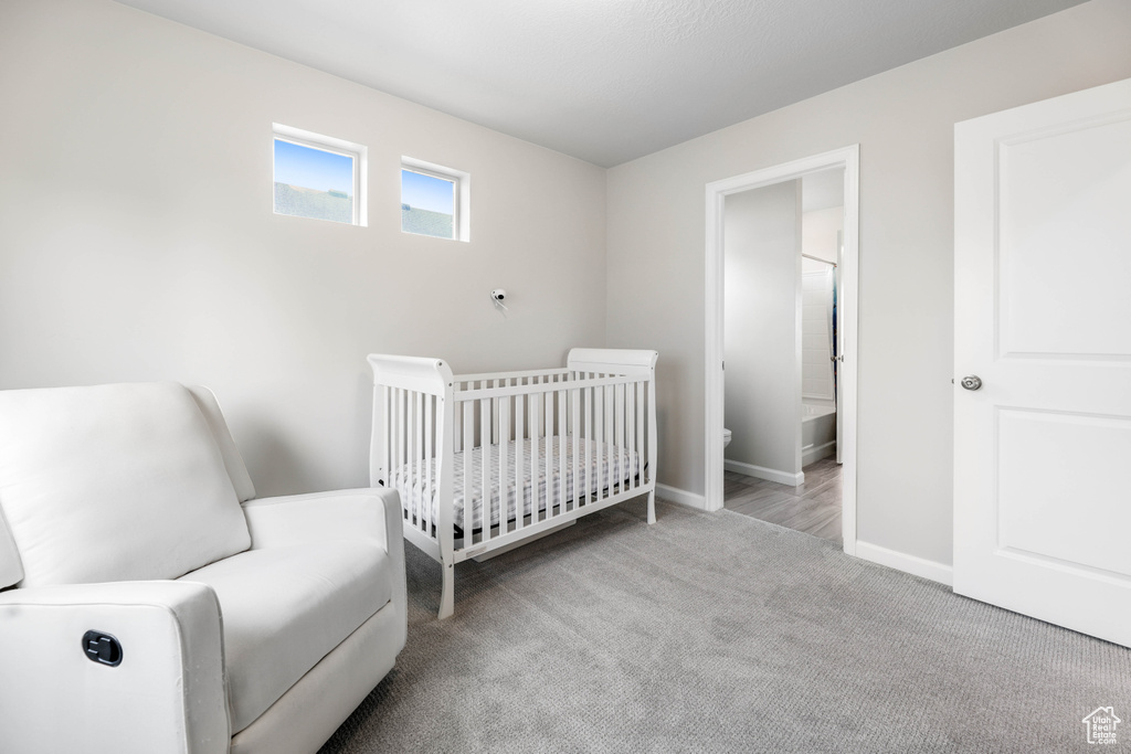 Carpeted bedroom with baseboards and a crib