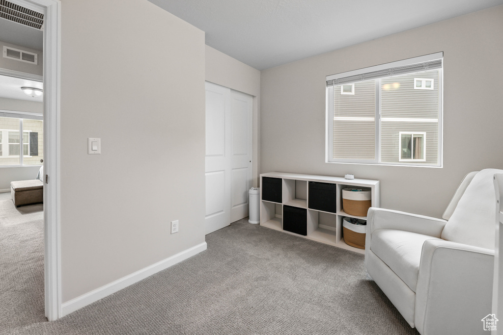 Sitting room with baseboards, visible vents, a healthy amount of sunlight, and carpet