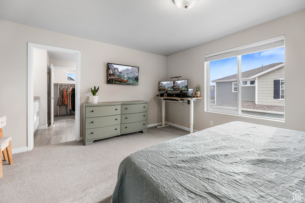 Bedroom with baseboards, carpet, and a walk in closet