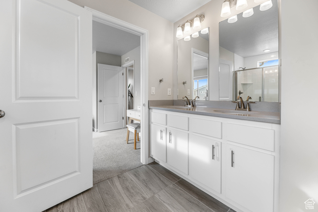 Bathroom with double vanity, a sink, an enclosed shower, and wood finished floors