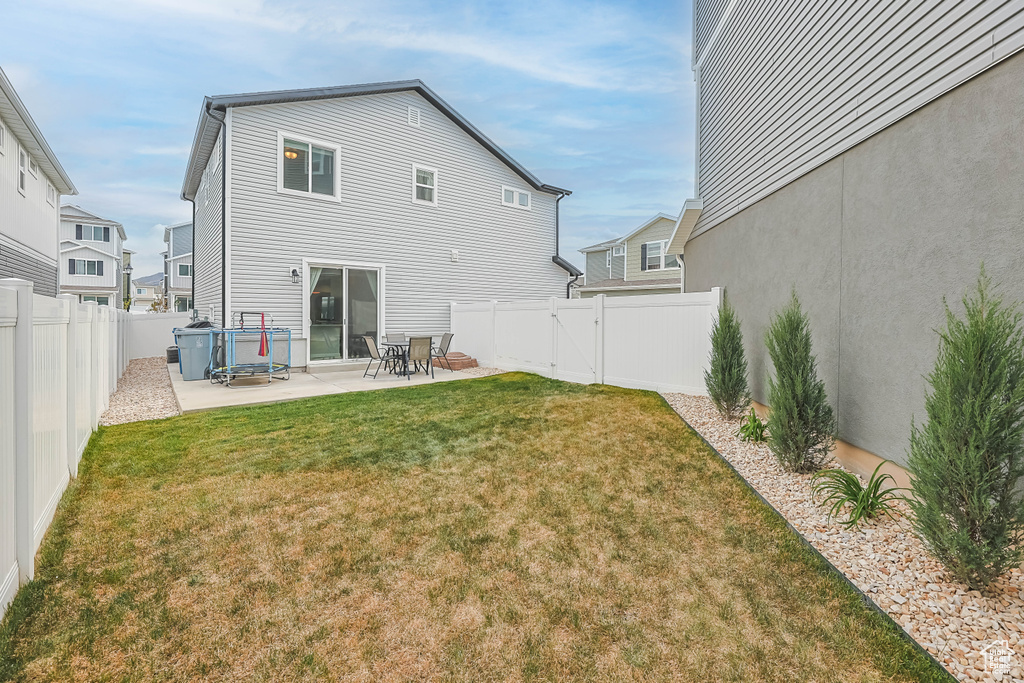Rear view of house with a lawn, a fenced backyard, and a patio area
