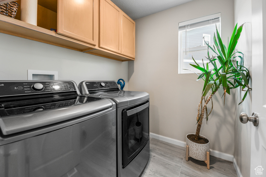 Laundry room featuring baseboards, light wood finished floors, independent washer and dryer, and cabinet space