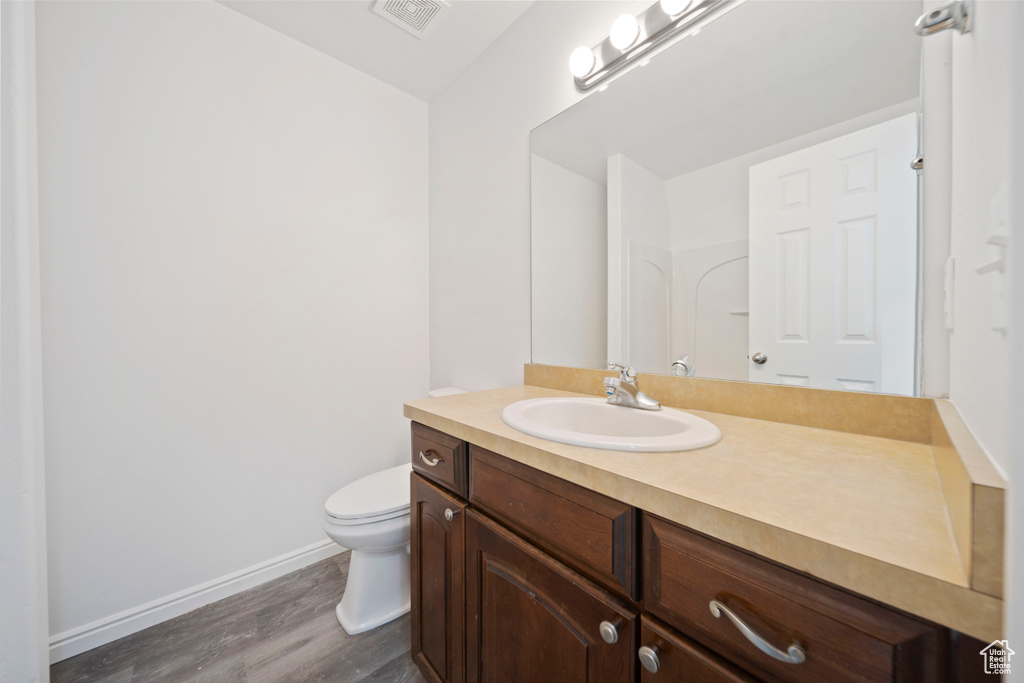 Bathroom featuring visible vents, vanity, wood finished floors, toilet, and baseboards