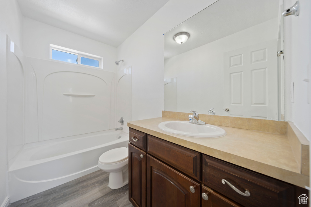 Full bathroom with bathing tub / shower combination, vanity, toilet, and wood finished floors