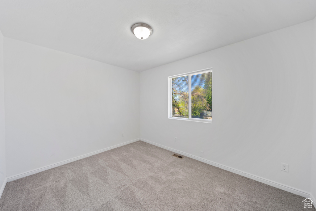 Carpeted empty room with baseboards and visible vents