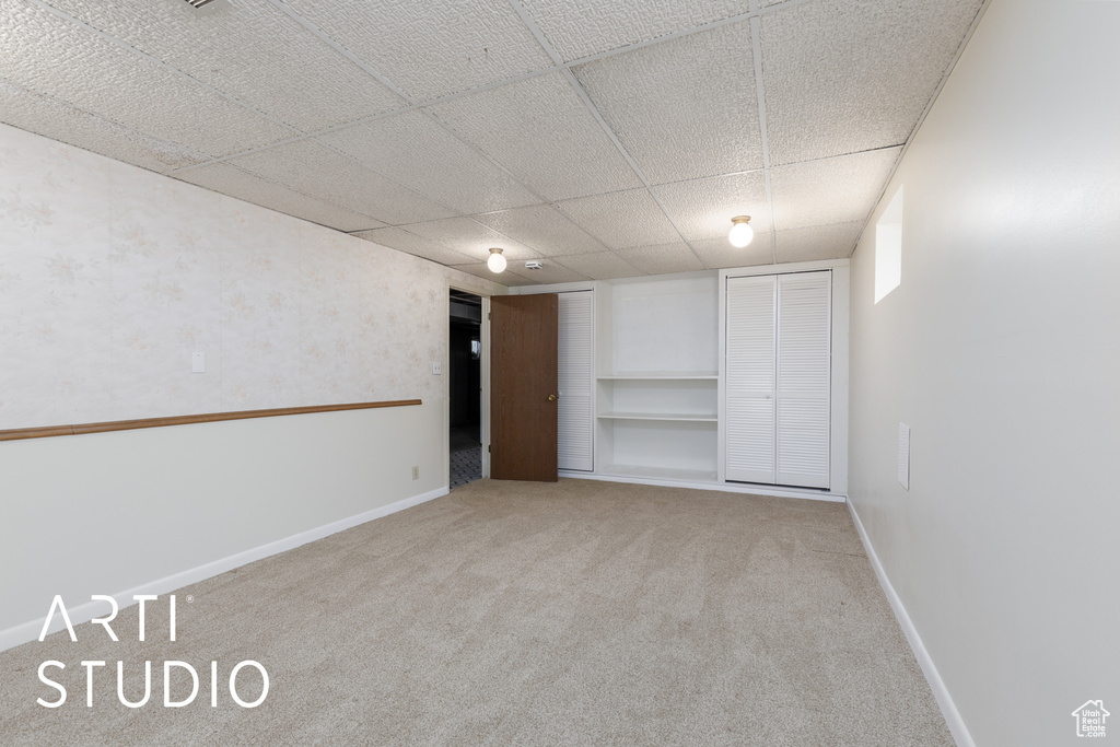 Unfurnished bedroom featuring carpet floors, baseboards, and a paneled ceiling