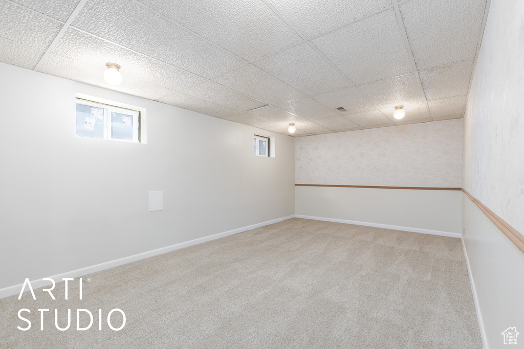 Below grade area with plenty of natural light, baseboards, carpet, and a drop ceiling