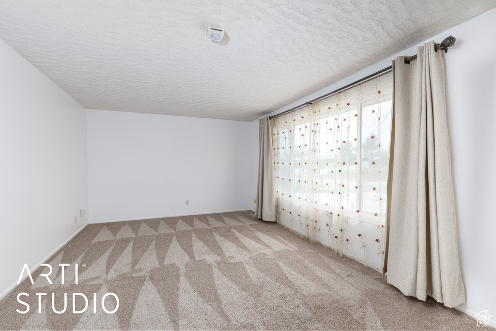 Carpeted empty room with a textured ceiling