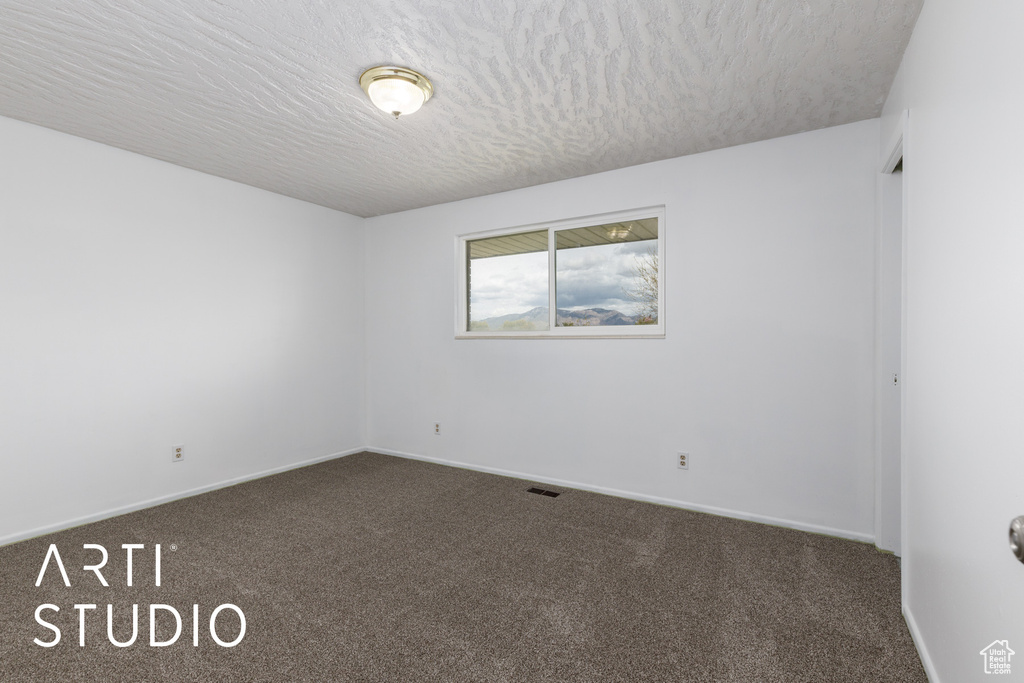 Unfurnished room with baseboards, a textured ceiling, and carpet