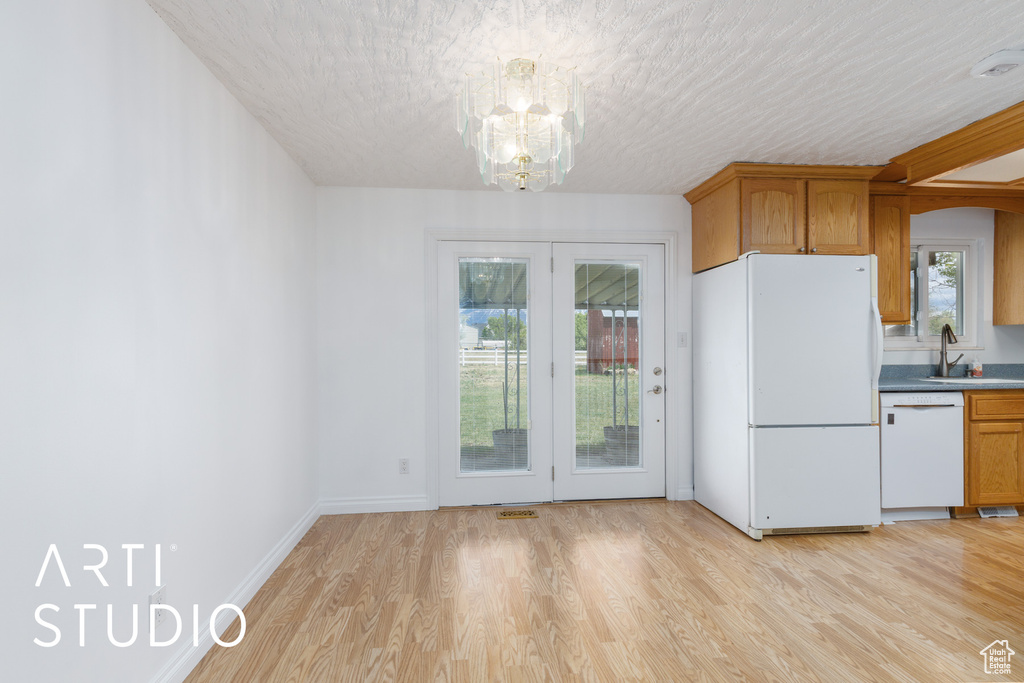 Kitchen with a sink, plenty of natural light, white appliances, and a notable chandelier