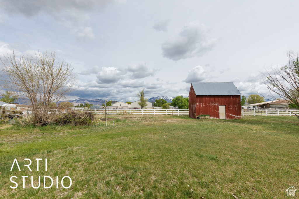 View of yard with a barn, fence, and an outbuilding