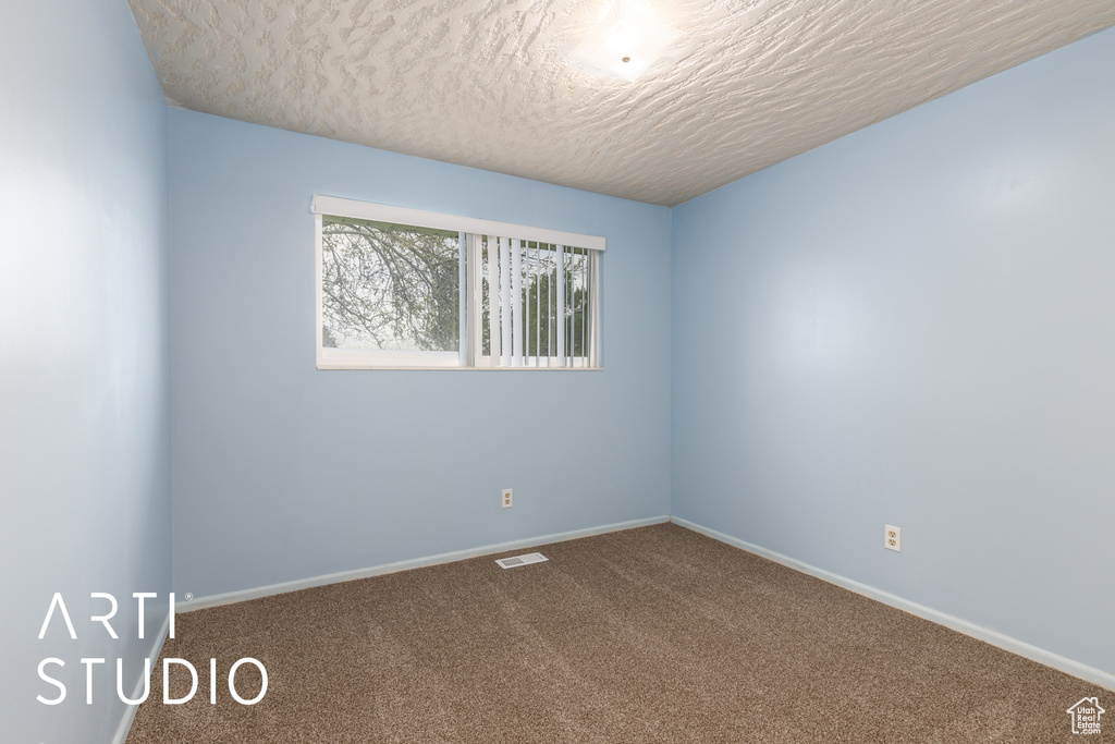 Carpeted empty room with a textured ceiling, baseboards, and visible vents