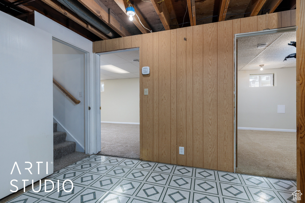 Spare room with baseboards, a drop ceiling, light carpet, and stairway