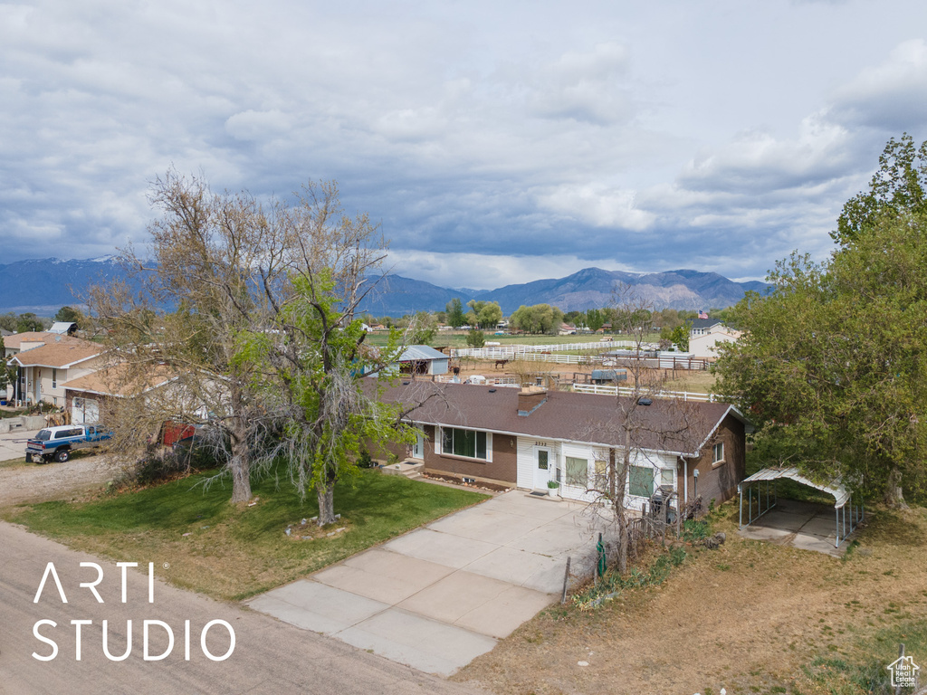 Ranch-style home featuring concrete driveway, a mountain view, a front yard, and a carport