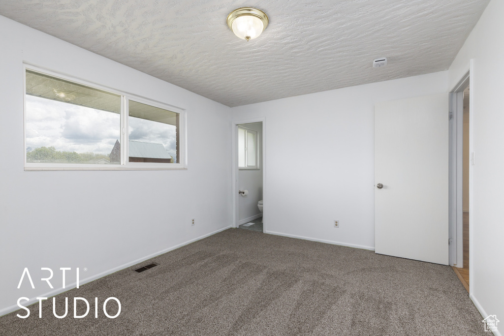 Carpeted spare room with baseboards, a textured ceiling, and visible vents