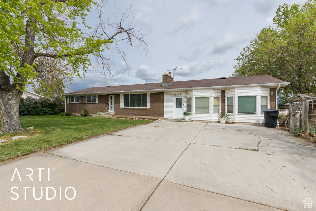 Ranch-style home featuring driveway, fence, a front yard, and a chimney