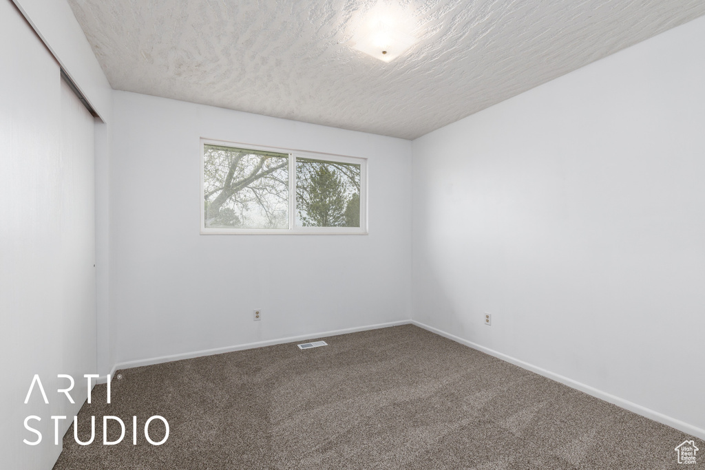 Unfurnished room featuring visible vents, a textured ceiling, carpet, and baseboards