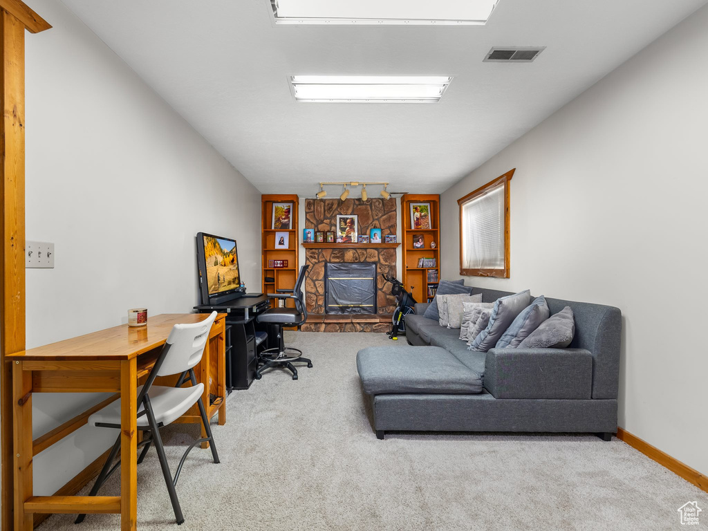 Home office featuring carpet floors, baseboards, a fireplace, and visible vents