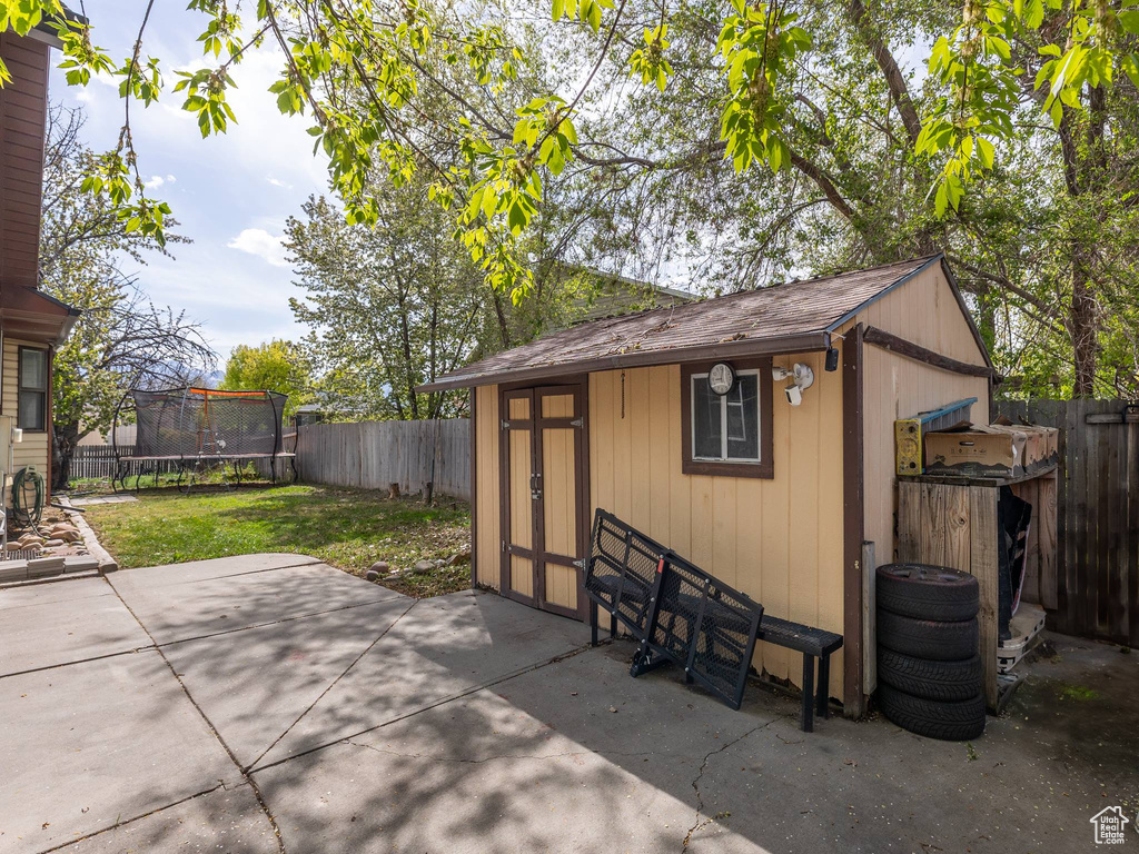 View of outbuilding featuring an outbuilding, a fenced backyard, and a trampoline