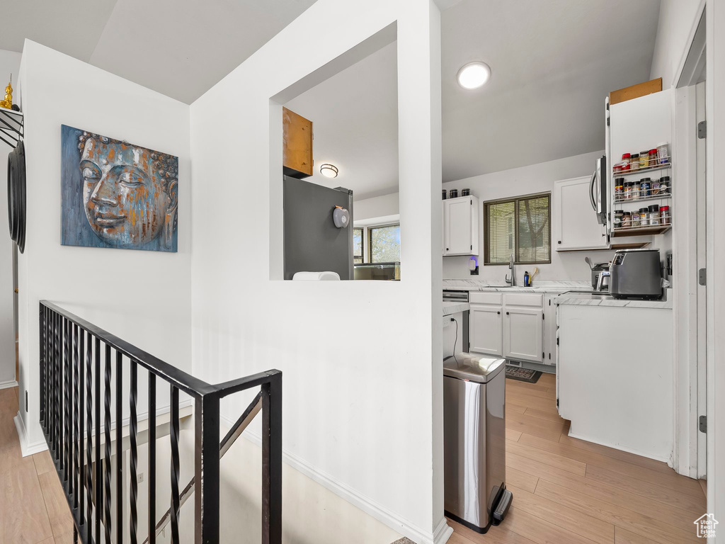 Kitchen featuring light countertops, white cabinets, a sink, and light wood-style flooring