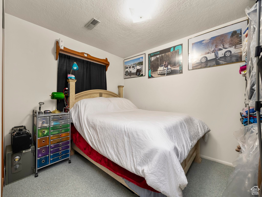 Bedroom featuring visible vents, carpet flooring, and a textured ceiling