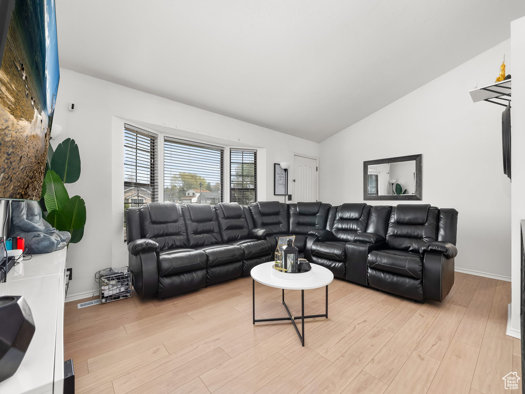 Living area featuring baseboards, vaulted ceiling, and light wood-style floors
