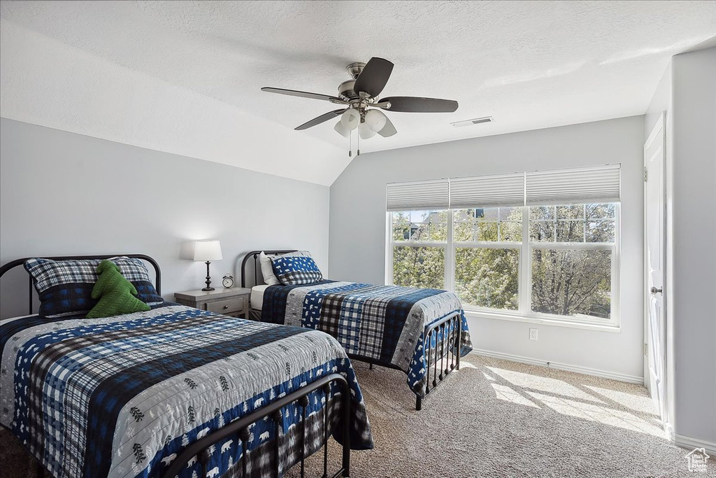 Carpeted bedroom with a ceiling fan, a textured ceiling, visible vents, baseboards, and lofted ceiling
