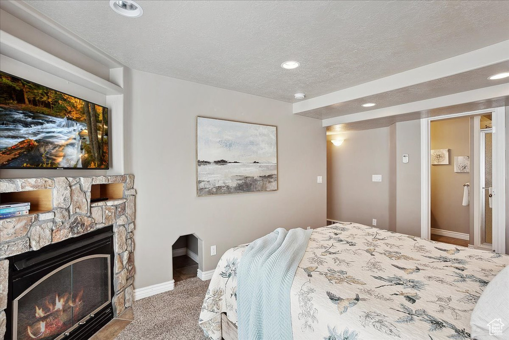 Bedroom with carpet floors, a fireplace, baseboards, recessed lighting, and a textured ceiling