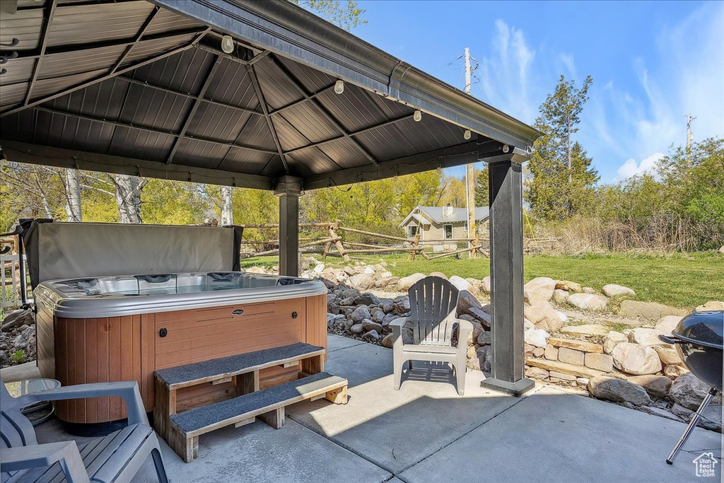 View of patio featuring a hot tub and a gazebo