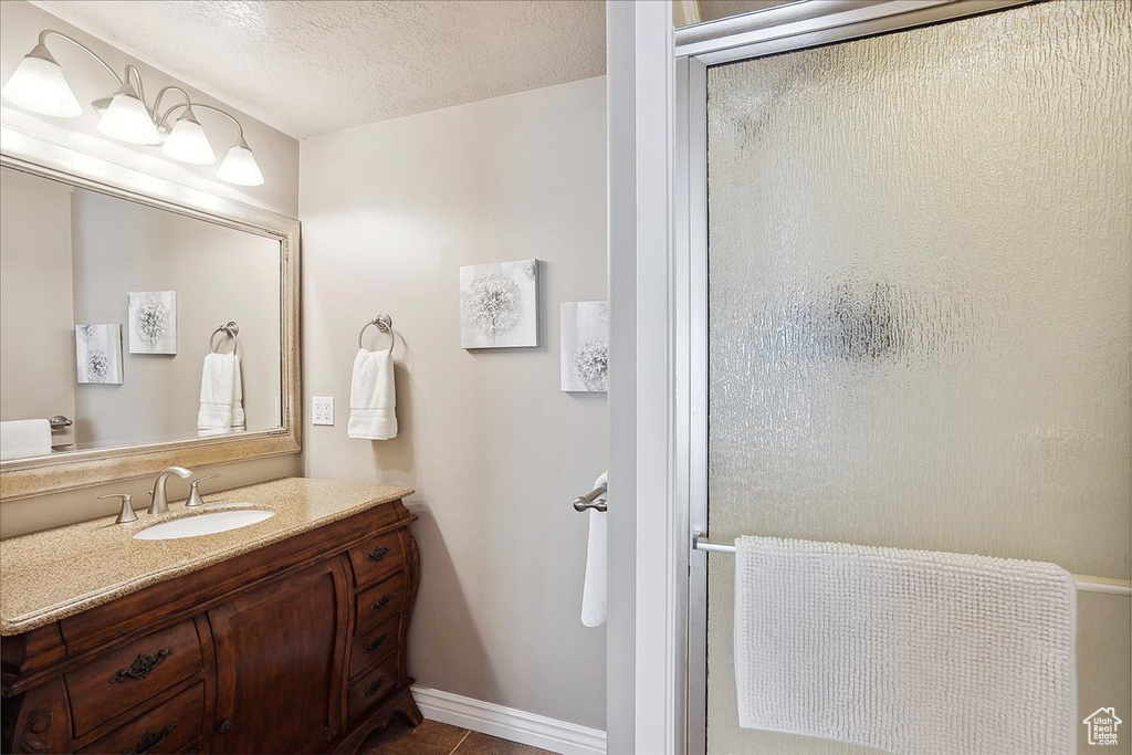 Full bath with vanity, a textured ceiling, tile patterned flooring, and a shower stall