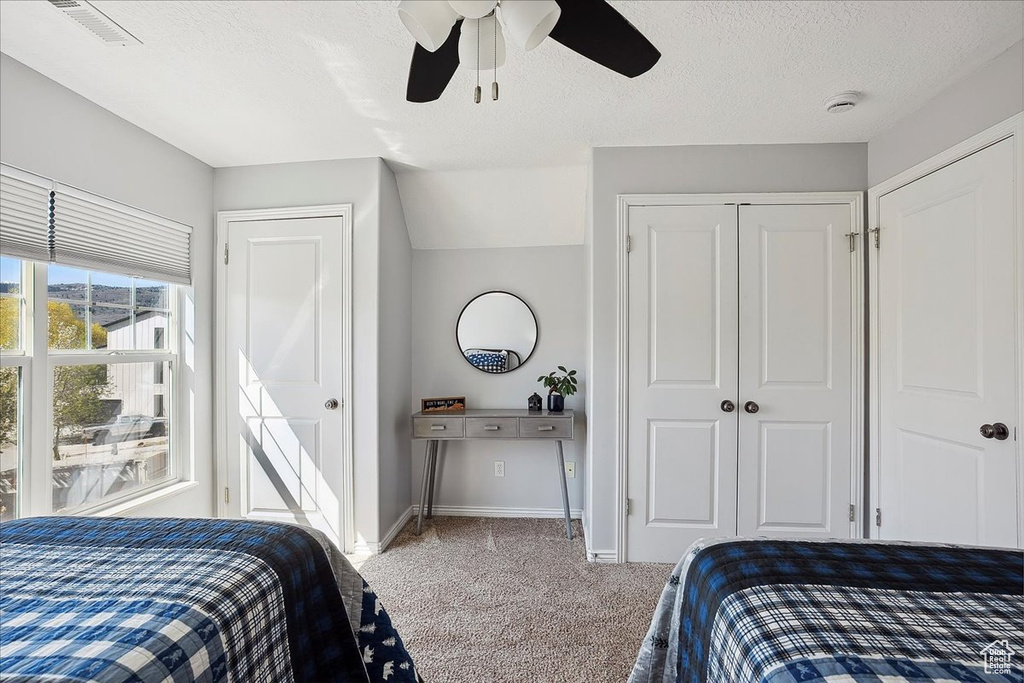 Bedroom with a ceiling fan, a textured ceiling, visible vents, baseboards, and carpet flooring