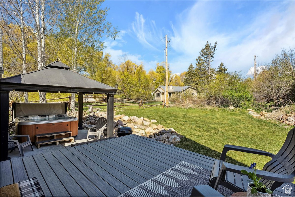 Wooden deck featuring a hot tub, a lawn, and a gazebo