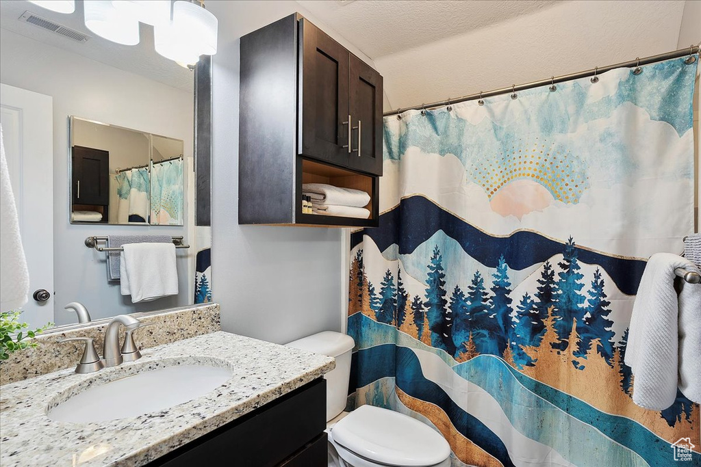 Bathroom featuring visible vents, a shower with curtain, toilet, and vanity