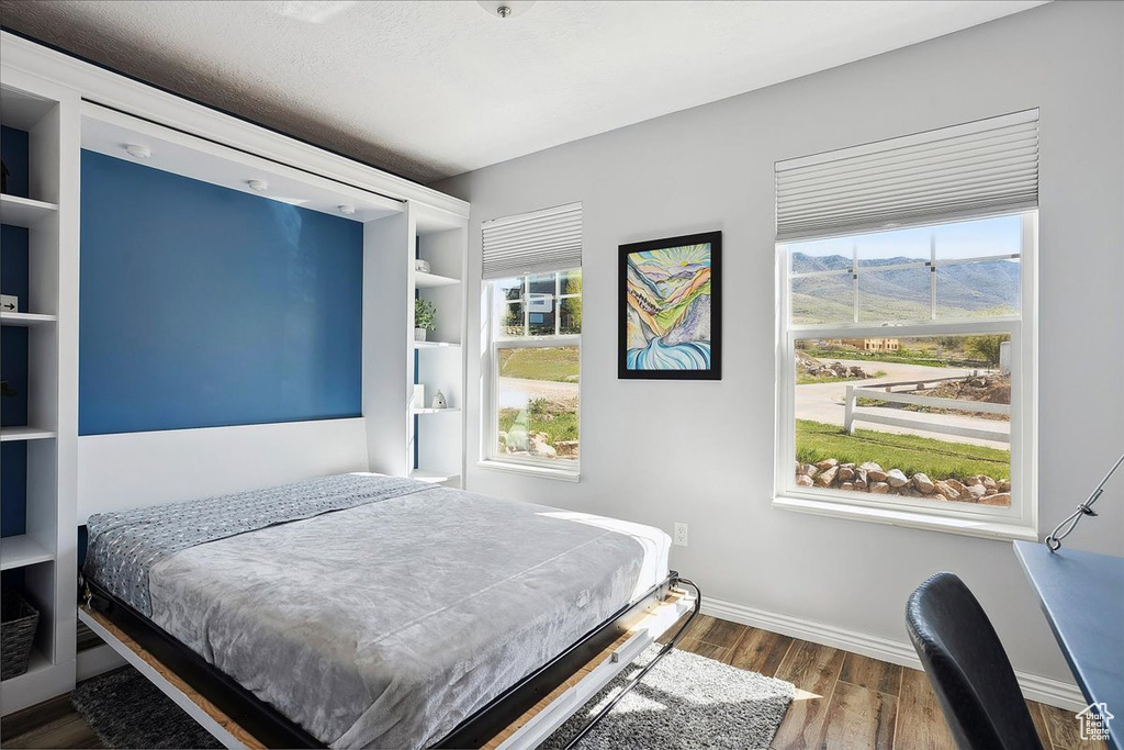 Bedroom featuring baseboards, a mountain view, and wood finished floors