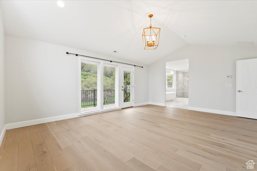 Interior space with baseboards, light wood-style floors, a chandelier, lofted ceiling, and recessed lighting