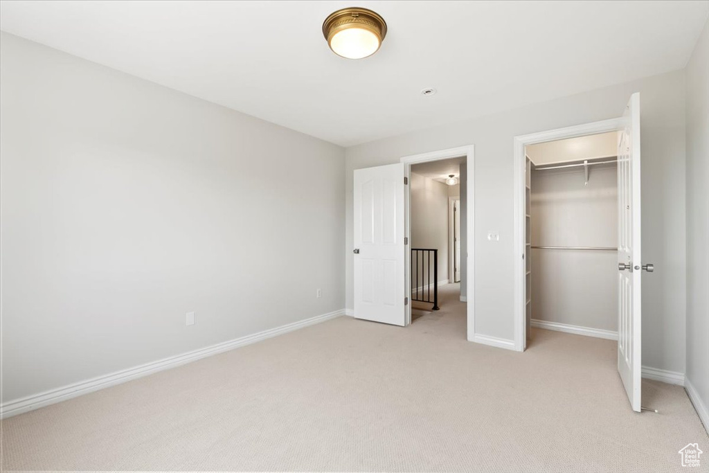 Unfurnished bedroom featuring baseboards, a closet, and light colored carpet