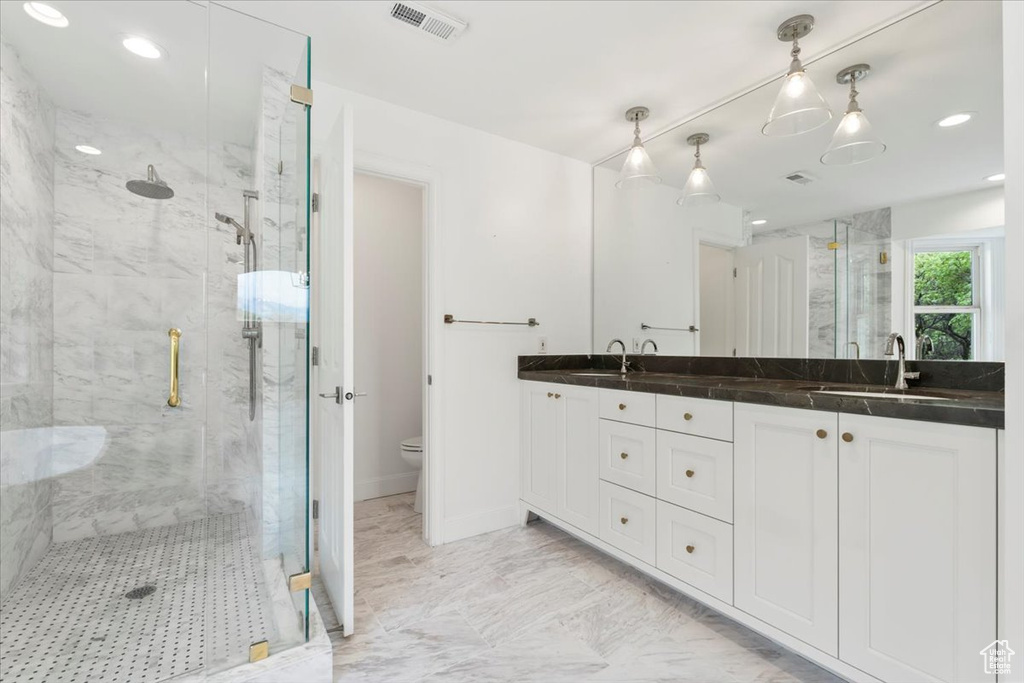 Bathroom featuring double vanity, toilet, a marble finish shower, a sink, and visible vents