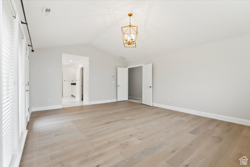 Interior space with light wood-style floors, a chandelier, baseboards, and lofted ceiling