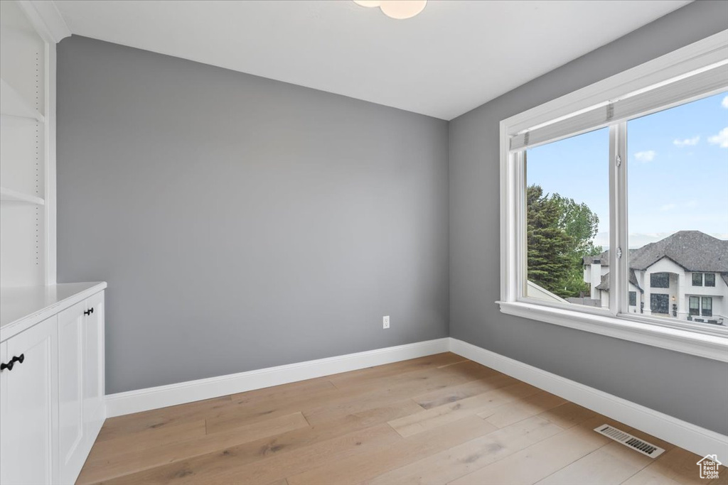 Empty room with baseboards, light wood finished floors, and visible vents