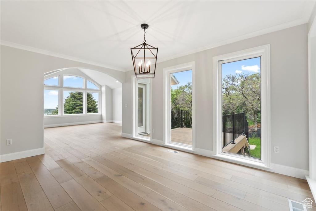 Unfurnished dining area with an inviting chandelier, light wood-type flooring, baseboards, and ornamental molding