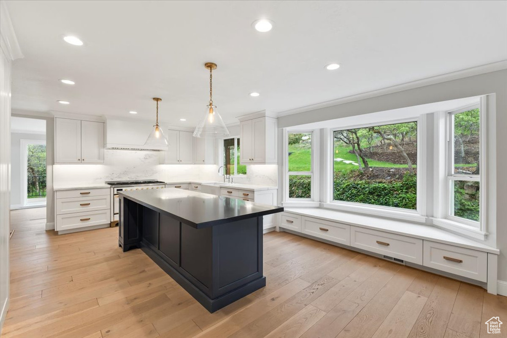 Kitchen with a sink, backsplash, white cabinets, and stainless steel range oven