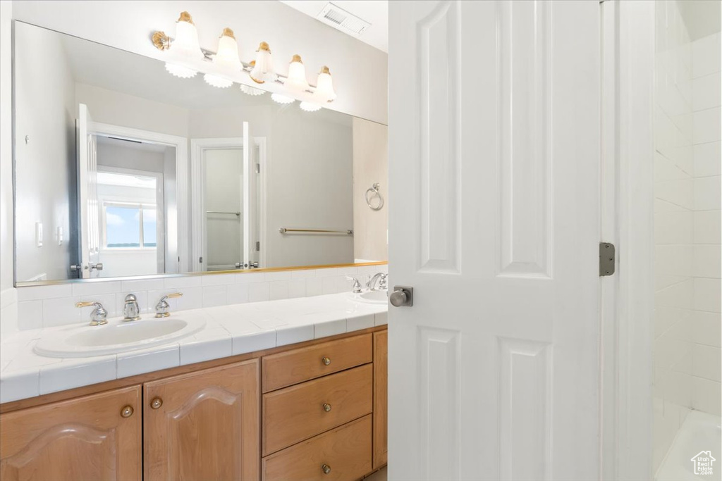 Bathroom with visible vents, double vanity, and a sink