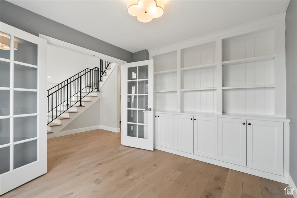 Entryway with light wood finished floors, stairs, baseboards, and french doors