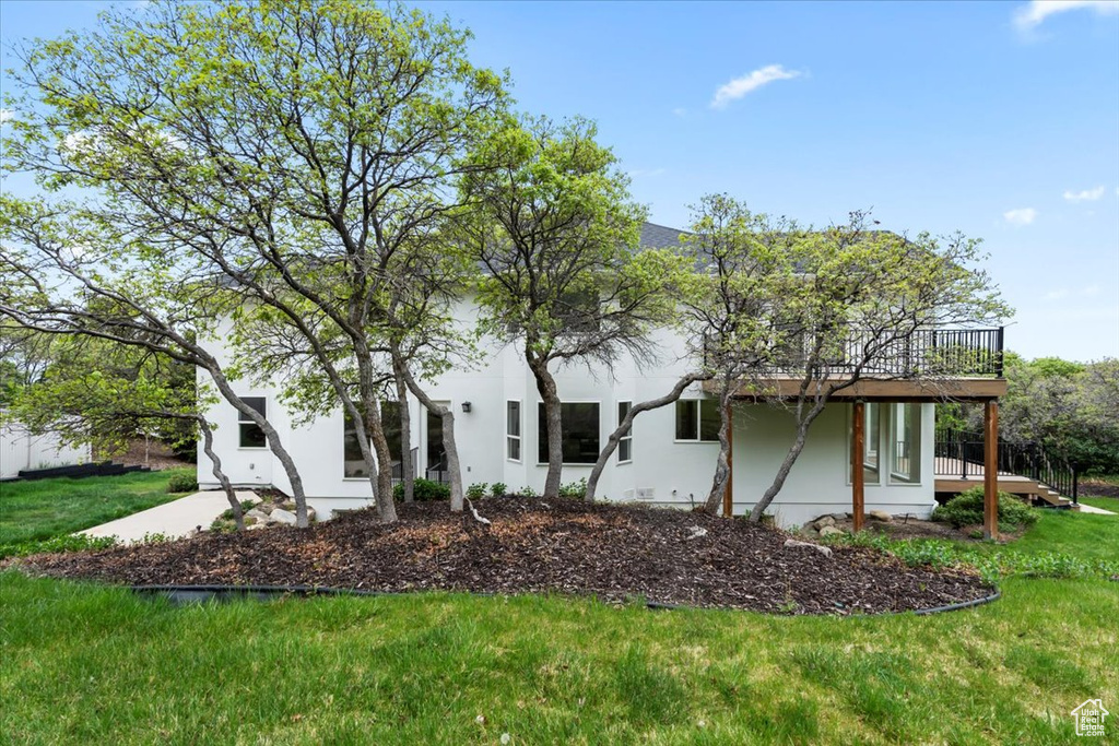 Exterior space with stucco siding, a deck, and a front lawn
