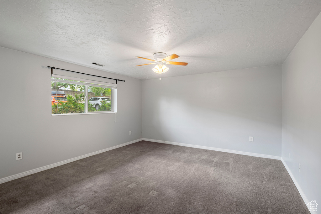 Empty room with carpet floors, a ceiling fan, a textured ceiling, and visible vents