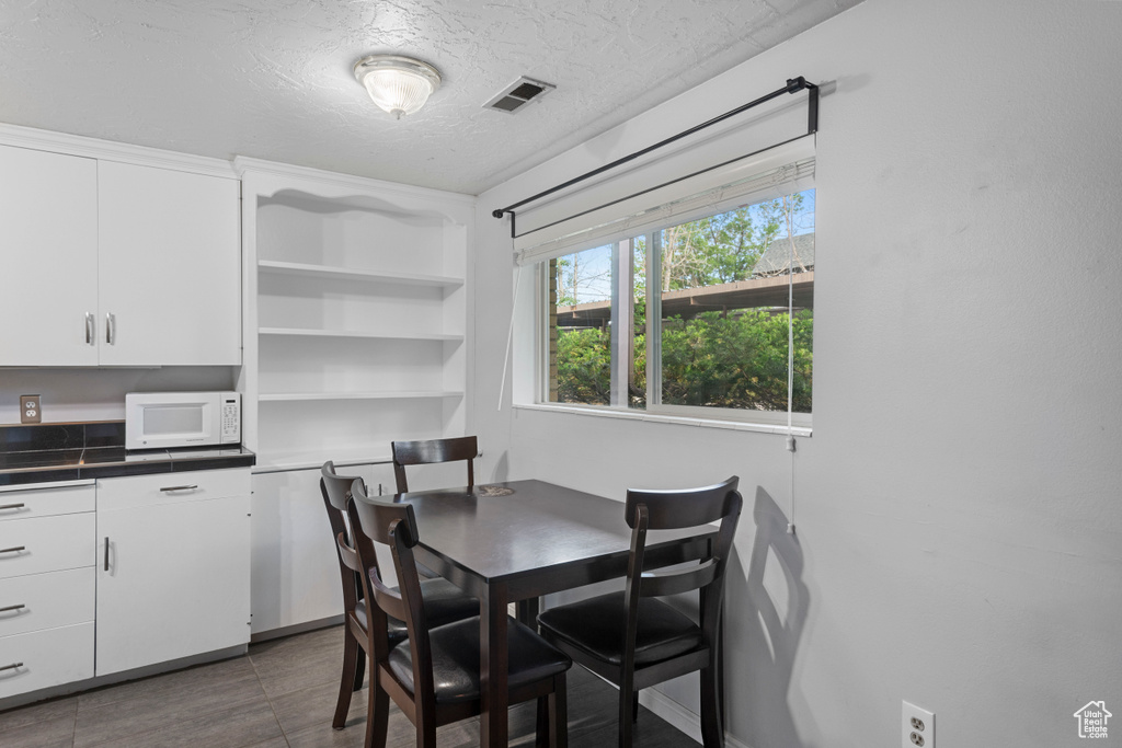 Dining area featuring visible vents, a textured ceiling, and dark tile patterned floors