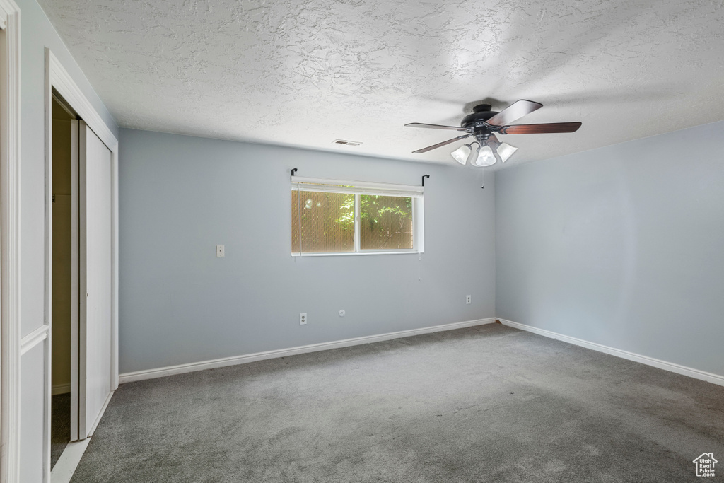 Unfurnished bedroom featuring carpet floors, a textured ceiling, visible vents, and a closet