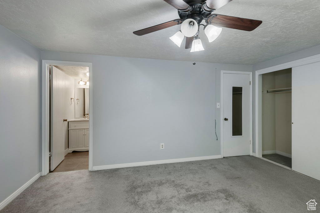 Unfurnished bedroom with carpet floors, a closet, baseboards, ensuite bathroom, and a textured ceiling