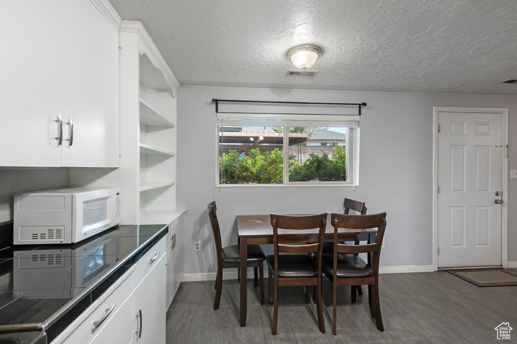 Dining area featuring a textured ceiling, baseboards, wood finished floors, and visible vents